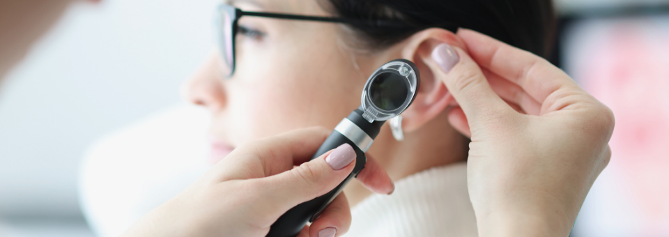 Audiologist checking patient's ear with otoscope
